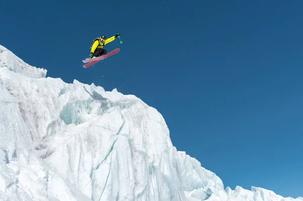 Ein springender Skifahrer, der von einem Gletscher gegen einen blauen Himmel hoch in den Bergen springt. professionelles Skifahren — Stockfoto