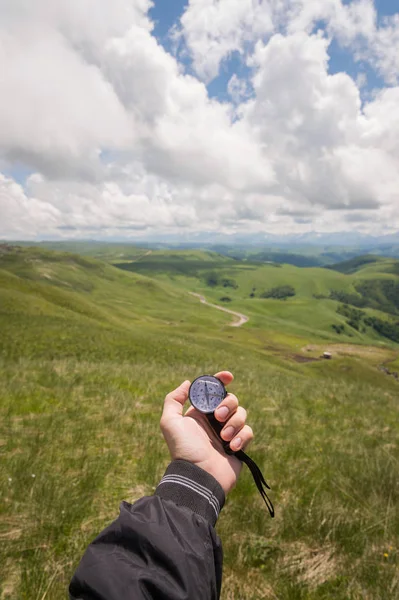 A mans ręka turysta z autentycznym kompas na tle górskiego krajobrazu — Zdjęcie stockowe