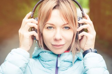 Müzik açık havada ormandaki kulaklık tutan güzel bir genç kadın portresi kapatın. Neşeli müzik