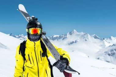 Bir kayakçı koruyucu bir kask ve gözlük portresi bir maske ve eşarp ile Kafkasya karla kaplı dağlar omzundan kayaklar olduğunu. Kayak,