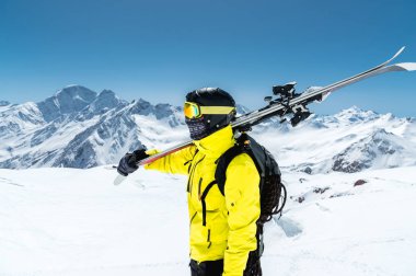 Bir kayakçı koruyucu bir kask ve gözlük portresi bir maske ve eşarp ile Kafkasya karla kaplı dağlar omzundan kayaklar olduğunu. Kayak,