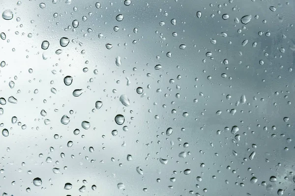 Textured background of window panes with a cloudy background. Natural pattern from a drop of rain on a cloudy background.