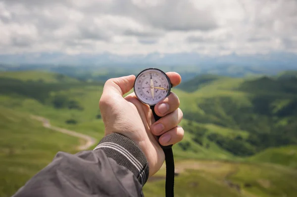 A bir dağ yolu manzara arka plan üzerinde otantik bir pusula ile el bir turist mans — Stok fotoğraf