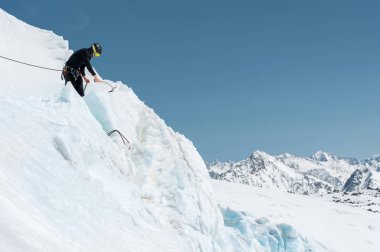 Profesyonel dağcı bir kask ve kar maskesi sigortası nick delikli beyaz karla kaplı dağlar zemin karşı buzul yapar