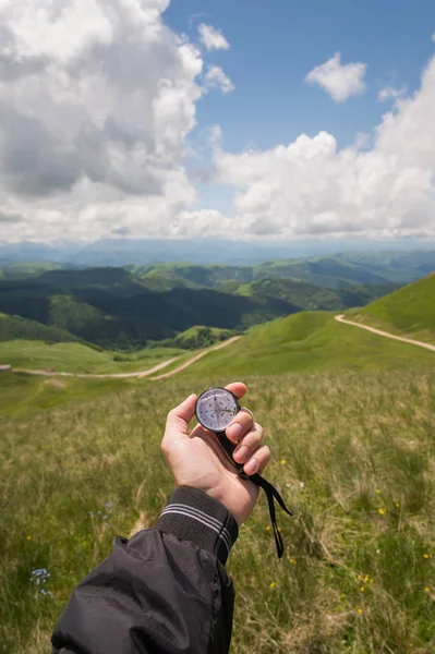 A mans hand turista s autentickou kompas na pozadí krajiny horské silnice — Stock fotografie