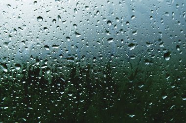 Her iki yağmur ve sisleme soyut görünümü, yağmur damlaları mavi cama cam ve bulanık manzara mavi ve yeşil geçişin üzerinde doğal arka plan damla