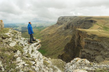 bir rock kenarında duran ve destansı bir plato üzerinde mesafe içine bakan sakallı hippi turist adam. Turizm kavramı