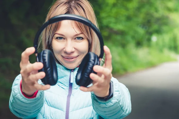 Szczęśliwa dziewczyna na zewnątrz w lesie posiada słuchawki. Koncepcja muzyki stereo gdziekolwiek. Walking muzyki — Zdjęcie stockowe