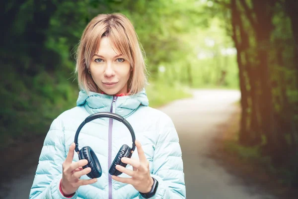 Szczęśliwa dziewczyna na zewnątrz w lesie posiada słuchawki. Koncepcja muzyki stereo gdziekolwiek. Walking muzyki — Zdjęcie stockowe