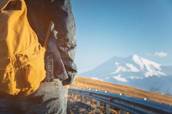 Bir sırt çantası arkasında arka plan bir dağın bir ülkede yol boyunca yürüyüş bir erkek gezgin Close-up. Boş dieser için kopyalayın. Yolculuk
