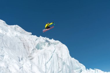 Bir mavi gök yüksek dağlarda karşı bir buzul üzerinden atlama atlama bir kayakçı. Profesyonel kayak