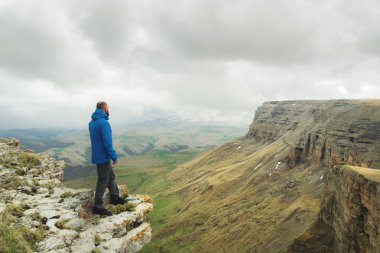 bir rock kenarında duran ve destansı bir plato üzerinde mesafe içine bakan sakallı hippi turist adam. Turizm kavramı
