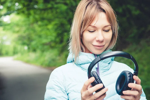 Szczęśliwa dziewczyna na zewnątrz w lesie posiada słuchawki. Koncepcja muzyki stereo gdziekolwiek. Walking muzyki — Zdjęcie stockowe