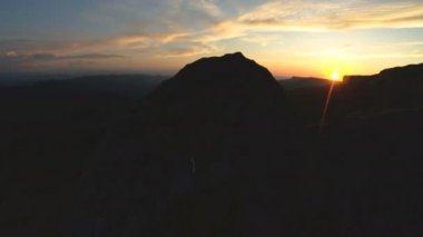 En yüksek kayanın üzerinde dağ günbatımı. Rock çimen Dağları paralaks anahtar günbatımı ışıkta karanlık kayalar