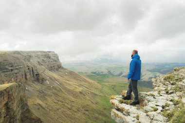 bir rock kenarında duran ve destansı bir plato üzerinde mesafe içine bakan sakallı hippi turist adam. Turizm kavramı
