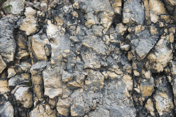 Piedras de guijarro en una pared rocosa. Fondo natural de un muro de piedra rocosa — Foto de Stock