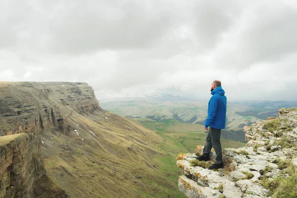 bir rock kenarında duran ve destansı bir plato üzerinde mesafe içine bakan sakallı hippi turist adam. Turizm kavramı