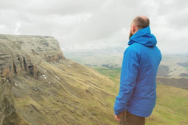 bir rock kenarında duran ve destansı bir plato üzerinde mesafe içine bakan sakallı hippi turist adam. Turizm kavramı