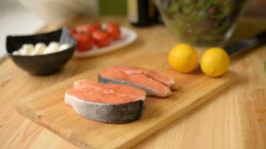 Bir tabloda alan nerede limon limon peynir ve domates somonlar evde bir salata yeşillikleri hazırlar sığ derinliği içinde yakın çekim