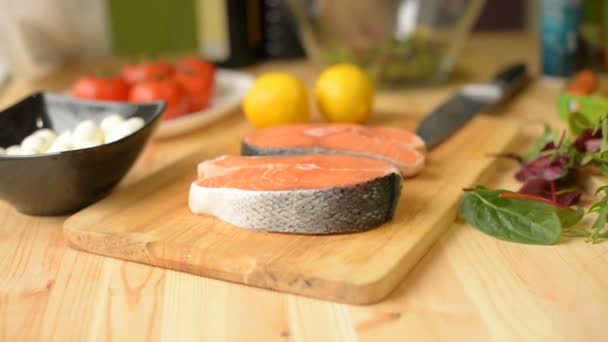 El primer plano en la profundidad poco profunda del campo en una mesa donde limón salmón queso y tomates chica en casa prepara una ensalada de verduras — Vídeos de Stock