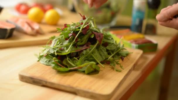 Detail v mělké hloubky ostrosti na stůl kde citron citron lososový sýr a rajčata dívka doma připravuje salát greeny — Stock video