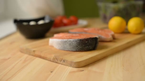 Крупный план на мелкой глубине поля на столе, где лимонный лосось сыр и помидоры девушка дома готовит салат из зелени — стоковое видео