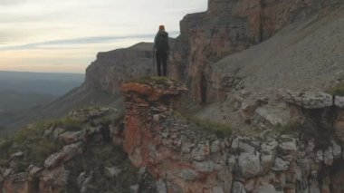Hava - top of Rock'tan epik Yaylası'nın eteklerinde günbatımında ulaşan bir sırt çantası ile genç bir yetişkin kadın hareket. Arkadan görüntüleyin. Rusya. Kuzey Kafkasya