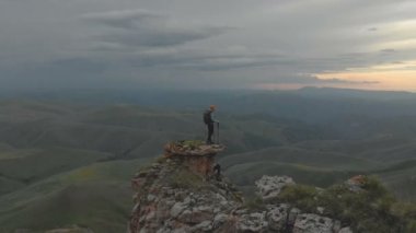 Hava - top of Rock'tan epik Yaylası'nın eteklerinde günbatımında ulaşan bir sırt çantası ile genç bir yetişkin kadın hareket. Arkadan görüntüleyin. Rusya. Kuzey Kafkasya