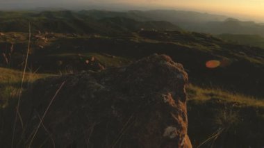 En yüksek kayanın üzerinde dağ günbatımı. Rock çimen Dağları paralaks anahtar günbatımı ışıkta karanlık kayalar