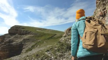 Arkadan şapkalı bir kız gidiyor fotoğrafçı tür. Bir turist fotoğrafçı ile bir sırt çantası ve elinde bir fotoğraf makinesi görünümü hayran uçurumun kayalıkbir platonun yürüyor. Yavaş