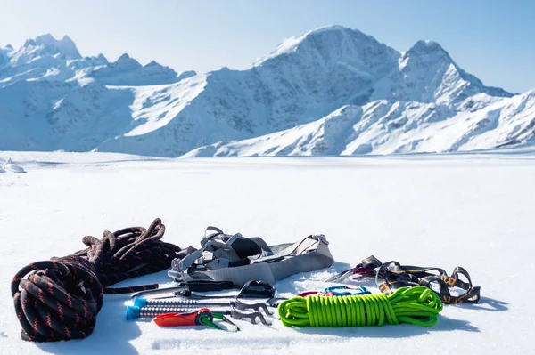Vinter uppsättning av utrustning av en is klättrare med karbinhake sår och en camp termos mot bakgrund av snöklädda berg. Kopiera utrymme för designer — Stockfoto