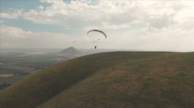 Atlet yamaçparaşütü yutar yanında onun paraglider üzerinde uçar. Drone çekim takip
