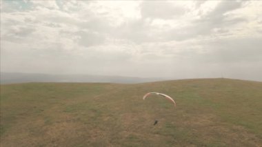 Atlet yamaçparaşütü yutar yanında onun paraglider üzerinde uçar. Drone çekim takip