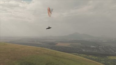 Atlet yamaçparaşütü yutar yanında onun paraglider üzerinde uçar. Drone çekim takip