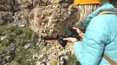 Sarışın kız fotoğrafçı kap içinde kayalar Kafkasya'da bir arka plan ile dijital kamera fotoğraf alır