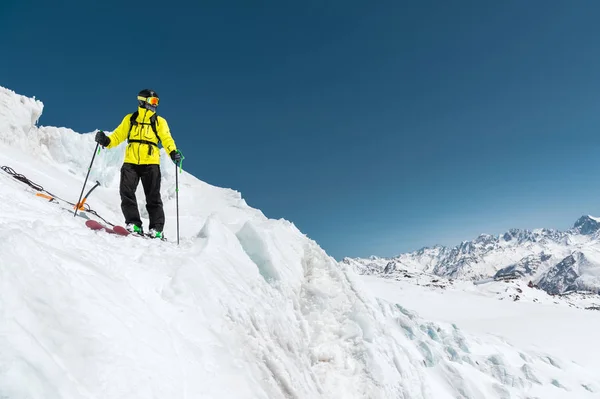 Un esquiador freerider en traje completo se encuentra en un glaciar en el Cáucaso Norte contra el fondo de las montañas cubiertas de nieve del Cáucaso — Foto de Stock