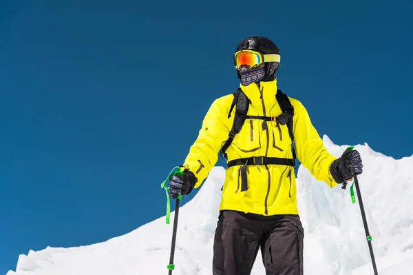 Bir yamaçta ayakta kayakçı. Biri hafif bir takım, kask ve maske içinde kayak kayak yapmak. Arka plan karla kaplı dağlara, kayakçı. Kafkas Dağları, Elbrus, Rusya Federasyonu — Stok fotoğraf