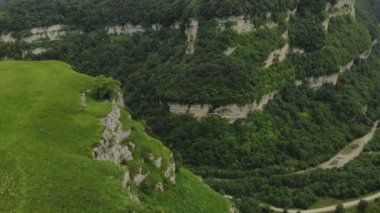 Gözlük ve şapka kız fotoğrafçı Yaylası yakınlarında uçurumun kenarına onun dslr fotoğraf makinesi ile yürür. Havadan görünümü