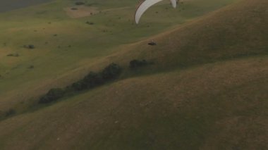 Atlet yamaçparaşütü yutar yanında onun paraglider üzerinde uçar. Drone çekim takip