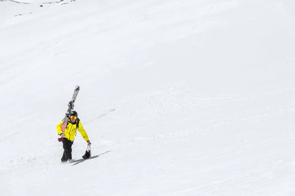 Un schior într-o cască și o mască cu un rucsac se ridică pe o pantă pe fundalul zăpezii și al unui ghețar. Backcountry Freeride — Fotografie, imagine de stoc