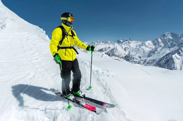 Uno sciatore freerider in completo si erge su un ghiacciaio nel Caucaso settentrionale sullo sfondo delle montagne innevate caucasiche — Foto Stock