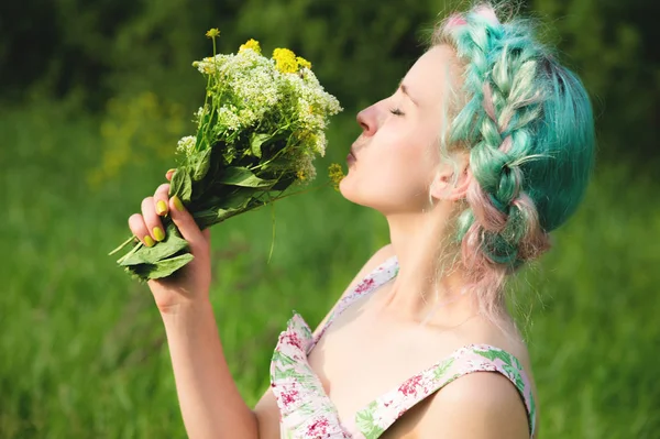 Carino ragazza sta annusando un mazzo di erba campo in natura. Armonia e divertimento nella natura — Foto Stock