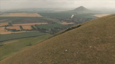 Atlet yamaçparaşütü yutar yanında onun paraglider üzerinde uçar. Drone çekim takip