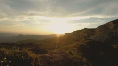Günbatımı gökyüzü bulutlu bir kayalık vadide içinde düşük bir anahtar. Gün batımında rock massif dibinde arazi Panoraması. 4 k ılık ışık