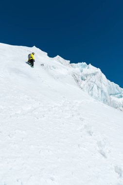 Bir kayakçı bir kask ve bir sırt çantası ile maske kar ve buzul arka planı bir yamaç üzerinde yükselir. Backcountry Freeride