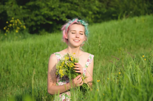 Portrait of a young happy smiling girl in a cotton dress with a bouquet of wildflowers — Stock Photo, Image