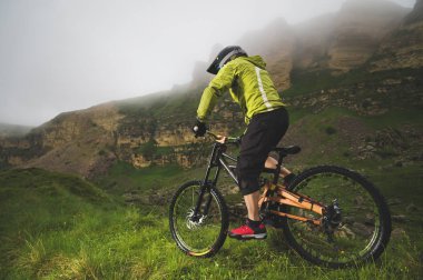 Bir adam bir dağ bisikleti binme bir dağ kask içinde güzel doğa bulutlu havalarda sürmek. yokuş aşağı