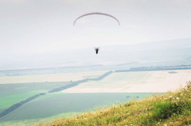 Bir koza arka planı, gökyüzü ve bulutlar bir yamaçparaşütü ile beyaz turuncu paraglide. Yamaç paraşütü spor