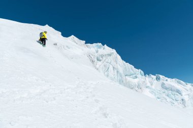 Bir kayakçı bir kask ve bir sırt çantası ile maske kar ve buzul arka planı bir yamaç üzerinde yükselir. Backcountry Freeride