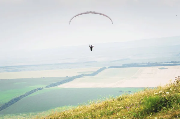 Parapente naranja blanco con un parapente en un capullo sobre el fondo de los campos del cielo y las nubes. Deportes de Parapente — Foto de Stock